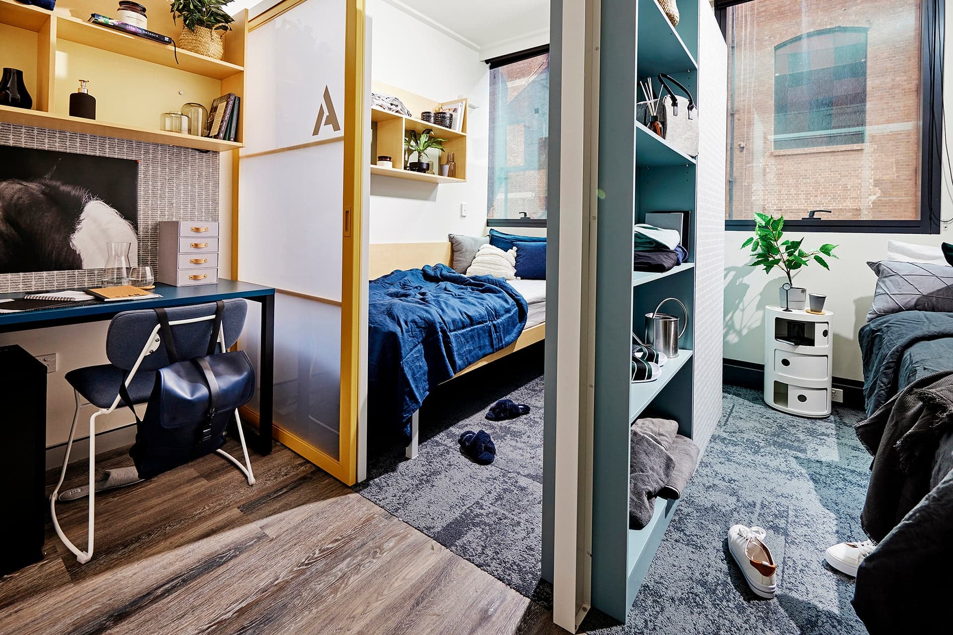 Desk and chair in front of sliding door and single bed in Scape bedroom.